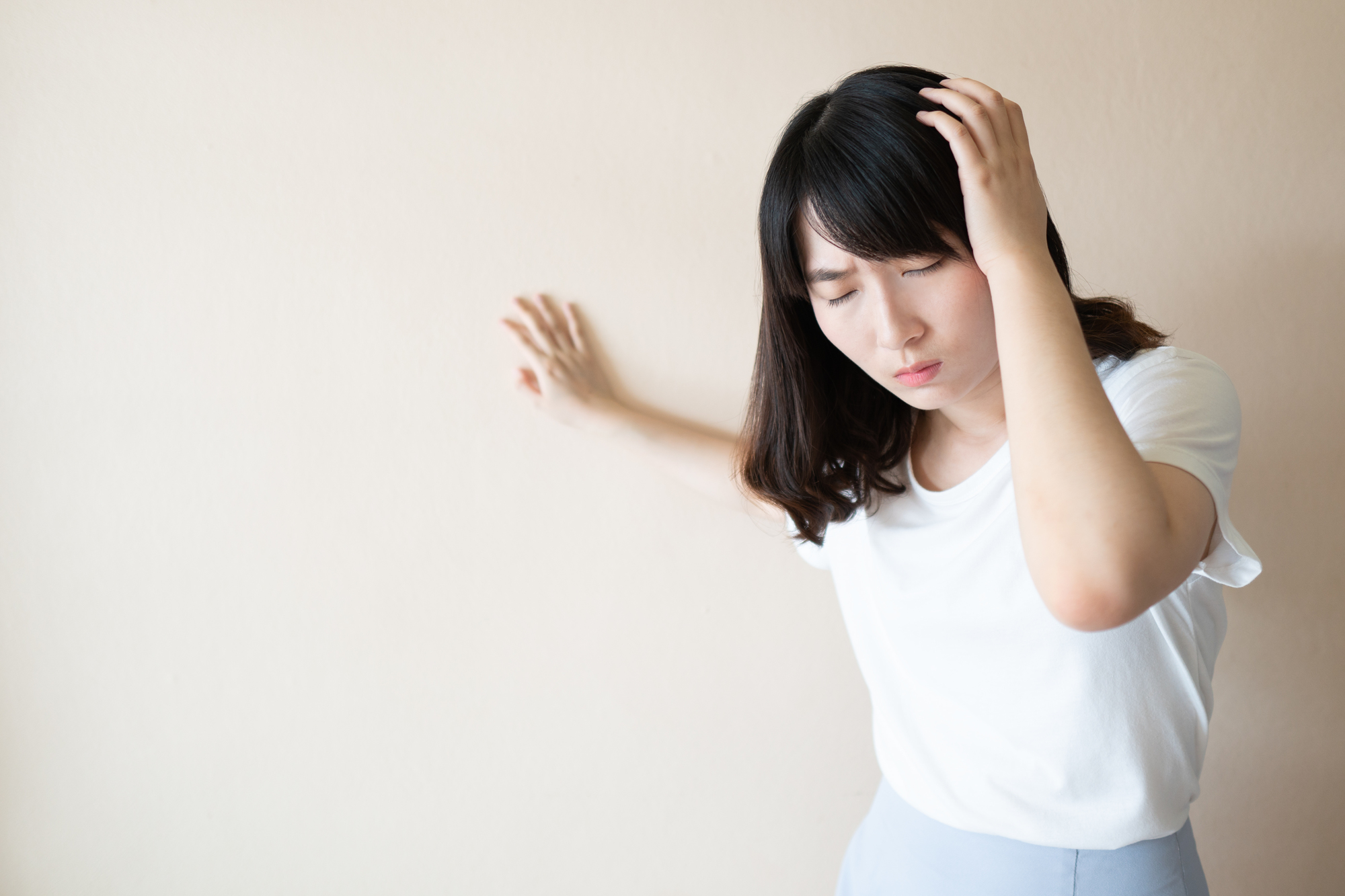  Young asian female suffering from dizziness, vertigo and headache over white background. Cause of dizzy inclued migraine, stress, stroke, BPPV, Meniere’s disease or brain tumor. Health care problem.